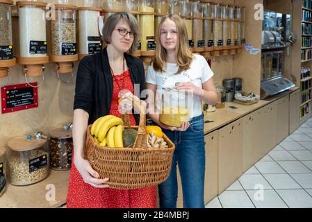Eine Frau und eine Schülerin stehen vor einem Regal mit Abfüllbehältern für Getreide im verpackungsfreien Laden „Frau Erna`s loser LebensMittelpunkt“ Stock Photo